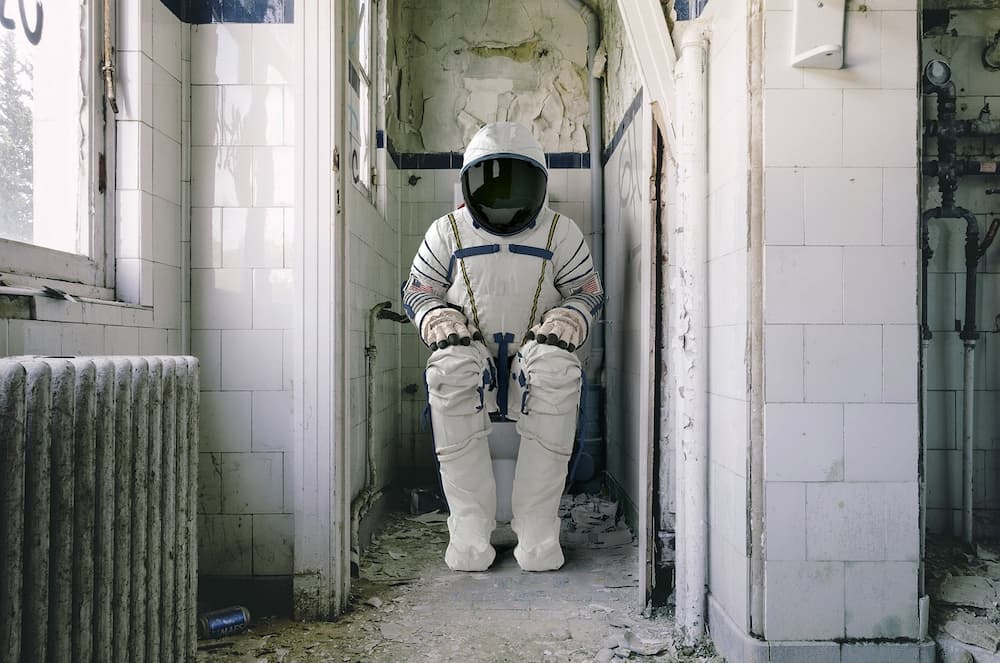 Astronaut sitting on a toilet with full space suit on