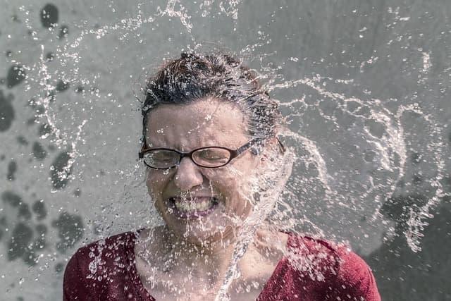cold water splashing on a woman's face from a broken gas water heater