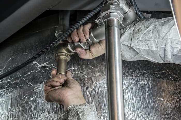 these hands fixing a pipe provide plumbing services 24/7 in Snohomish county